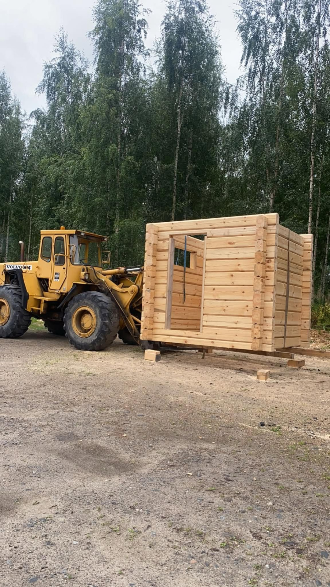 Pyöräkuormaaja siirtää valmista hirsikehikkoa metsätyömaalla.